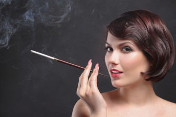 Young woman smoking with cigarette holder on dark background
