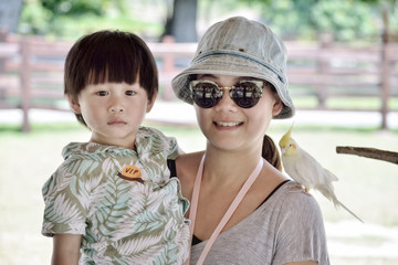 Mother with her son and bird looking at the camera in the zoo