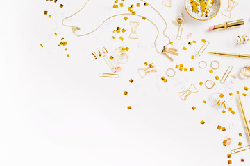 Beauty blog background. Gold style feminine accessories. Golden tinsel, scissors, pen, rings, necklace, bracelet on white background. Flat lay, top view.