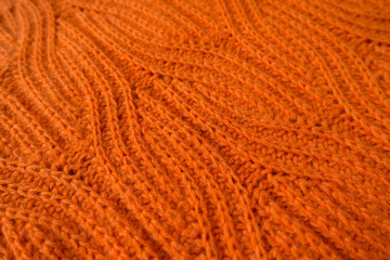 Close-up of bright orange handmade knit fabric with plait pattern (diagonal)