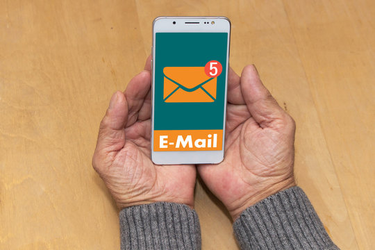 An elderly man holding a mobile phone  with icon online messages. The concept received an e-mail message online.