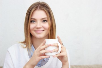 woman sitting on couch in her living room and drinking coffee