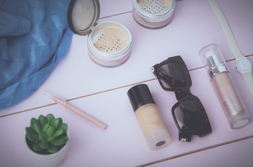 Sunglasses, cosmetics makeup and essentials on wooden background