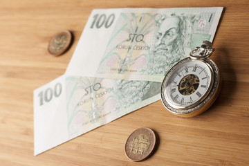 Time is money concept .Czech crowns on wooden background. Vintage watch.