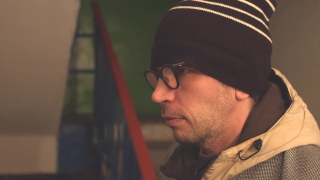 Face of a man close-up in profile.
Suspicious man in a hat and glasses close-up.
Serious, concentrated expression.