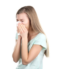 Young woman blowing nose on tissue against white background