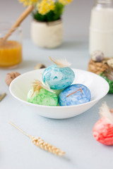Green, yellow and blue easter eggs on ceramic bowl, bright and airy shot.