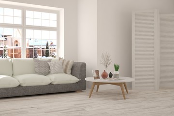 Fototapeta premium White room with sofa and urban landscape in window. Scandinavian interior design. 3D illustration