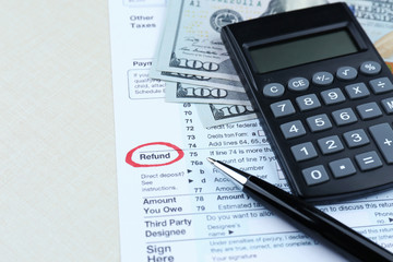Tax form, calculator and dollars on table