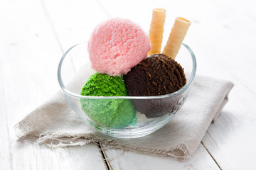 Ice cream scoops in crystal bowl on white wooden background. 
