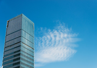 Modern glass building skyscrapers over blue sky.