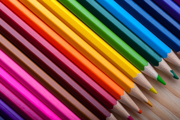 Fototapeta premium Multicolored pencils on wooden table, top view.