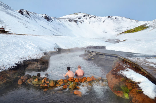 Fototapeta People sitting in Hot river in Iceland in winter snowy mountains
