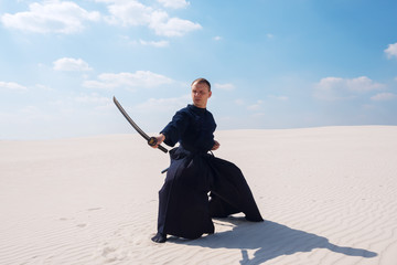 Confident man with a sword in his hands stands in low position