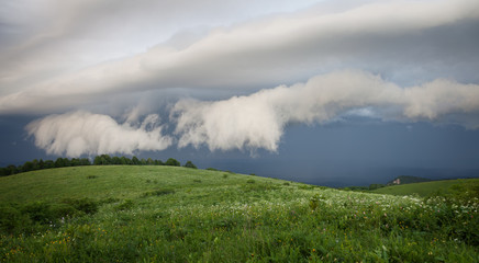 Green hills with lush green grass under cloudy sky