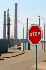 Stop sign at the approach of industrial zone. Warning of dangerous area ahead.