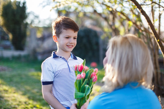 Little boy surprise mother with tulips outdoor, Mother's day