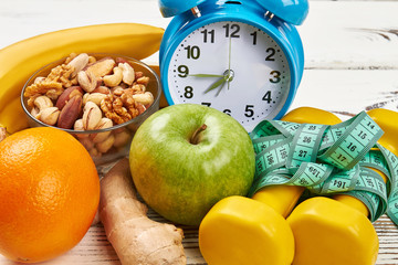 Alarm clock, dumbbells and apple. Eat and sleep rightl.