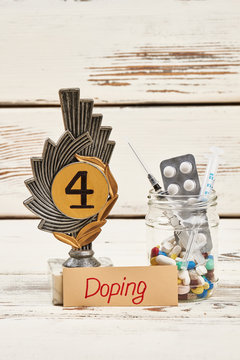 Reward and pills on wood. Negative effects of doping.
