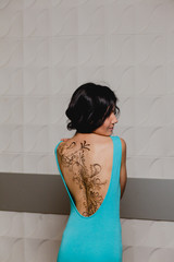 Slender brunette with henna ornaments drawn on her back