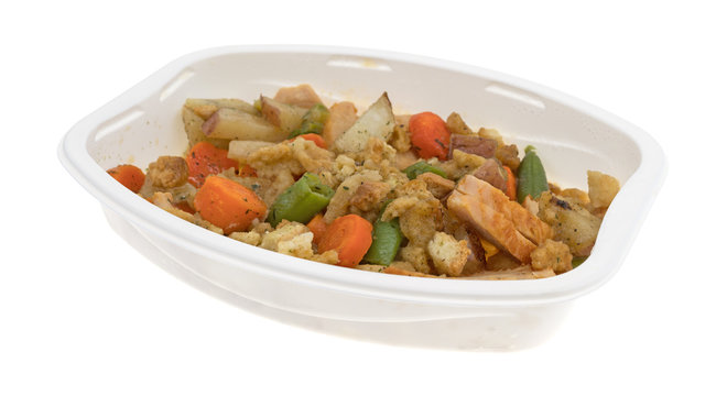 TV dinner of turkey breast with stuffing and vegetables isolated on a white background.