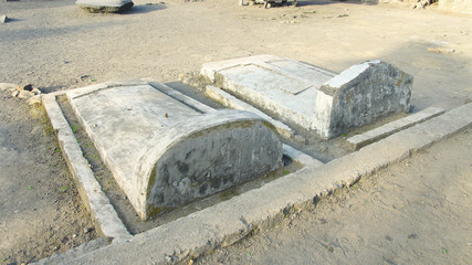 Two grey colored stone graves with tombstones at Bena a traditional village of the Ngada people in Flores near Bajawa, Indonesia.