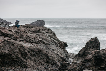 Fototapeta na wymiar Photographer at a precipice over a river soot landscape 