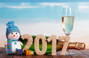 Digits 2017 twined with twine, snowman, champagne and New Year's gifts on table against sea