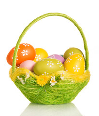 Colored Easter eggs in basket isolated on white background.