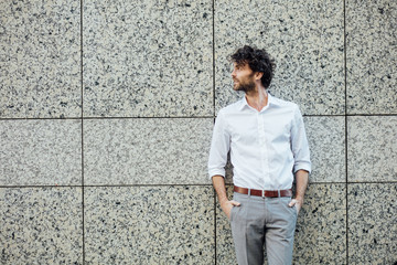handsome elegant man stanting outside against a gray wall