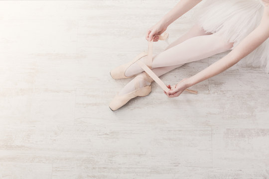 Ballerina puts on pointe ballet shoes, graceful legs
