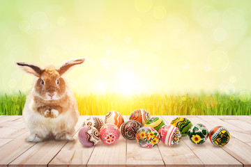 color full easter eggs and Brown Rabbit on wood and green bokeh in flare light for Easter festival Background