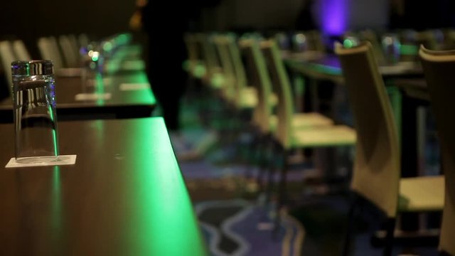 Bottles with water and transparent glasses on tables in meeting or conference hall. Getting rea