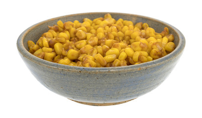 Barbecue seasoned corn in an old stoneware bowl isolated on a white background.