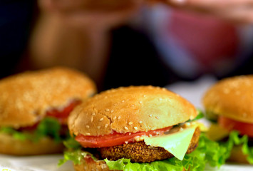 Hamburger fast food with ham on wooden board . Group of hamburger. Piece of cheese hanging from sandwich on blurry field.