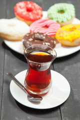 Cup of tea and donuts on a black wooden background