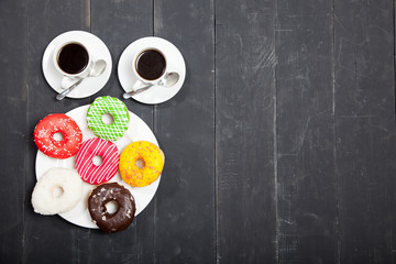 Two cups with coffee and donuts on a black wooden table