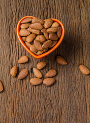 almond in porcelain heart bowl on wooden board