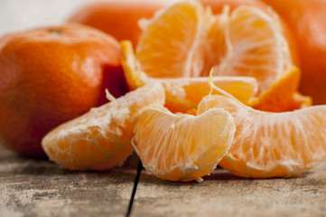 Ripe Mandarin fruit peeled open and place on old rustic look timber