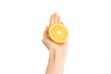 Healthy eating and diet Topic: Human hand holding a half of orange isolated on a white background in the studio, first-person view