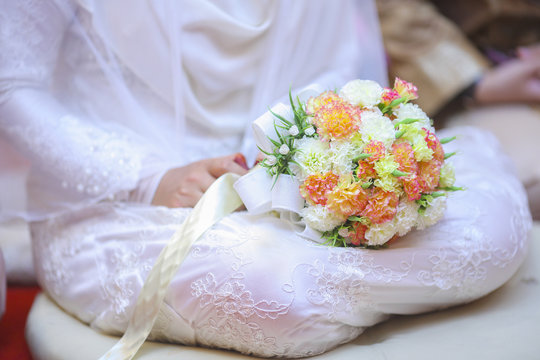 Bride with white dress holding a wedding flower.