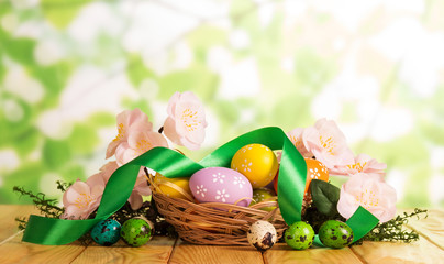 Fototapeta na wymiar Easter eggs in basket and outside, grass, flowers, ribbon.