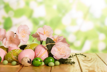 Easter eggs, candy, grass, flowers and ribbon on abstract green.