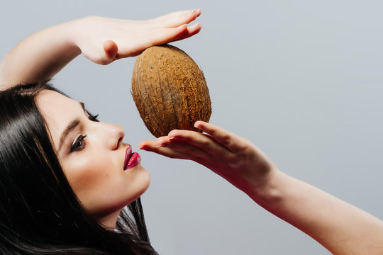 Beautiful woman with coconut in hands over white background, fashion portrait