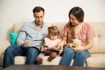 Family of three reading to their daughter