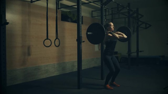 Beautiful young woman training lifting heavy barbells in gym. Locked down real time 4K video.
