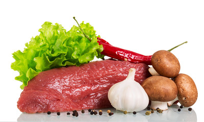 A piece of raw beef, mushrooms, lettuce, garlic and black pepper isolated on white.