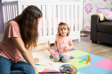 Happy girl painting with her nanny