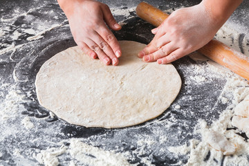 Obraz premium Baking concept. Hands roll dough on black background.