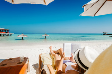 Woman on sunbed reading book under parasol at tropical island © Ivan Kurmyshov